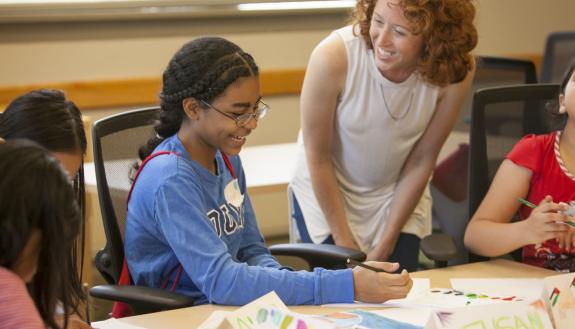 Graduate intern Samantha Boyce assists a student from Sudan with her art project. Photo by Jared Lazarus