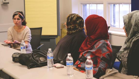 Medical student Rayan Kaakati, a member of a Bass Connections team, talks with refugees living in Durham.