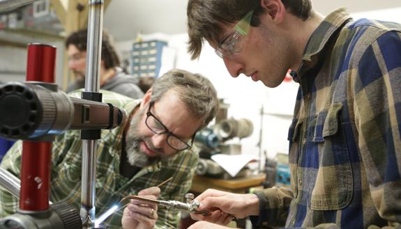Jim Kish, Owner, Kish Fabrication works with Duke Spring Breakthrough student in making a bicycle. Photo by Julie Schoonmaker