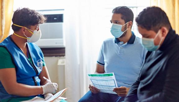 Nurse-Community-Family Partnership Program team member Diego Guaman, left, meets with a family in their home.