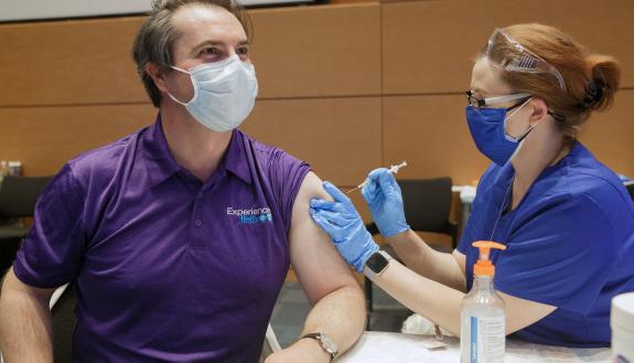 John Yeatts, an internal medicine doctor, left, gets his COVID-19 vaccine from Crystal Adams, a nursing informatics systems specialist at Duke. Photo by Shawn Rocco.