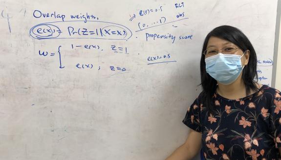 Statistical science professor Fan Li in front of. a whiteboard