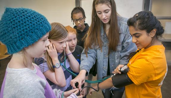 Durham area students learned how to perform a blood pressure check during a FEMMES session taught by Duke EMS, an all-volunteer, student-run division of the police department and Duke Life Flight. Duke senior Kayla Corredera-Wells (center) put the blood p