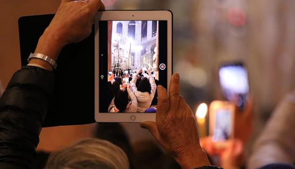 image of a person using a pad computer to record worship service in church