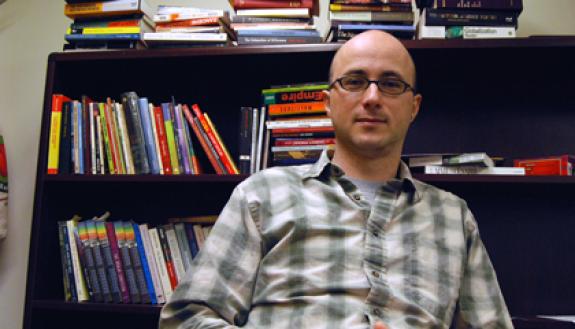 Gustavo Furtado poses by some of the many books decorating his office. Photo by Bryan Roth.