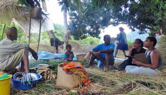 Ajilé, Fifi and Dezy Kely conducting an interview with participant Edmond while he and his family harvest rice in his field
