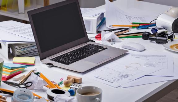 A messy desk with a laptop