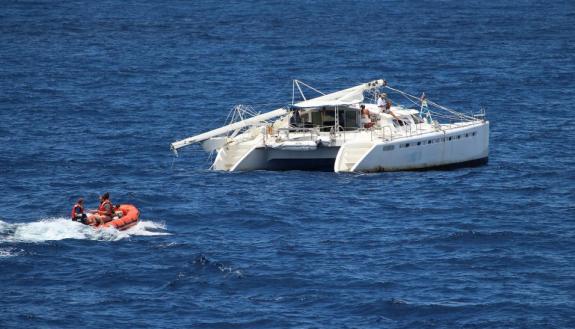 Crew members approaching the boat. Note the broken mast.
