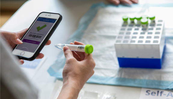 A Duke student is using a cellphone app to scan a vial of saline solution provided in the COVID self-testing kit.