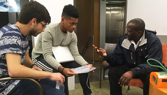 Students talk with Ugandan pediatric surgeon Nasser Kakembo to go over the design of the surgical silo. 