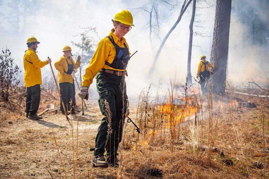 Sara Childs holds a drip torch lighting brush on fire