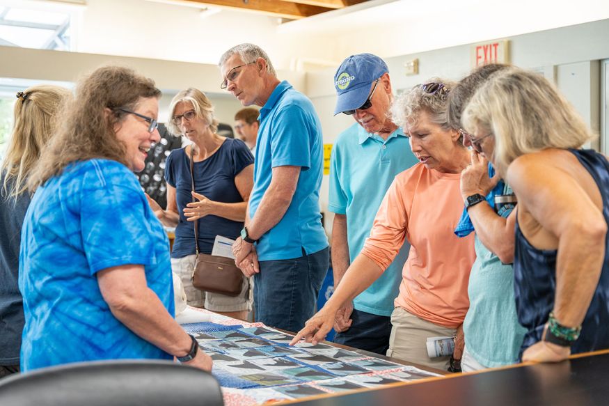 People gathered around a table while an employee talks about the images on the table