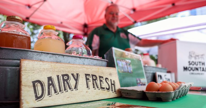 A dairy fresh sign rests next to a carton of eggs and a vendor selling goods from South Mountain Creamery